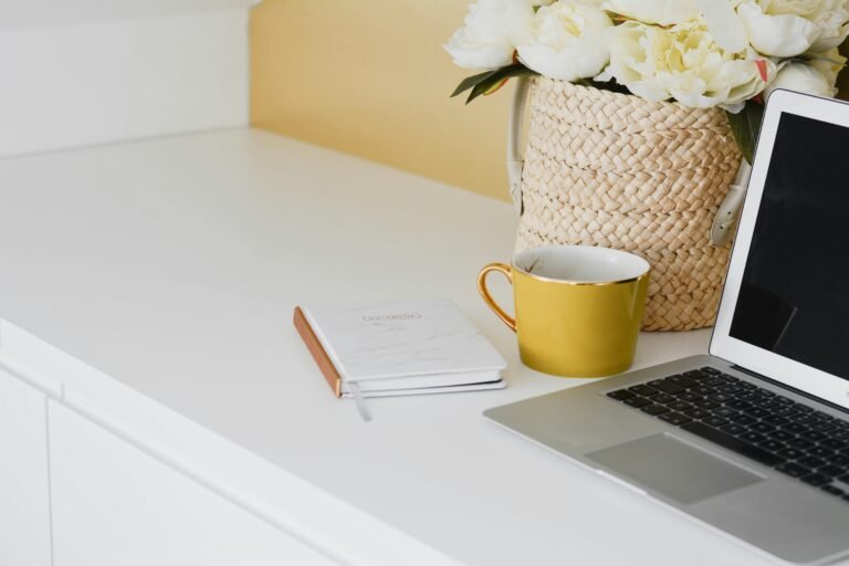 Clean home office desk with laptop, notebook, coffee mug, and flowers used for tenant screening work.